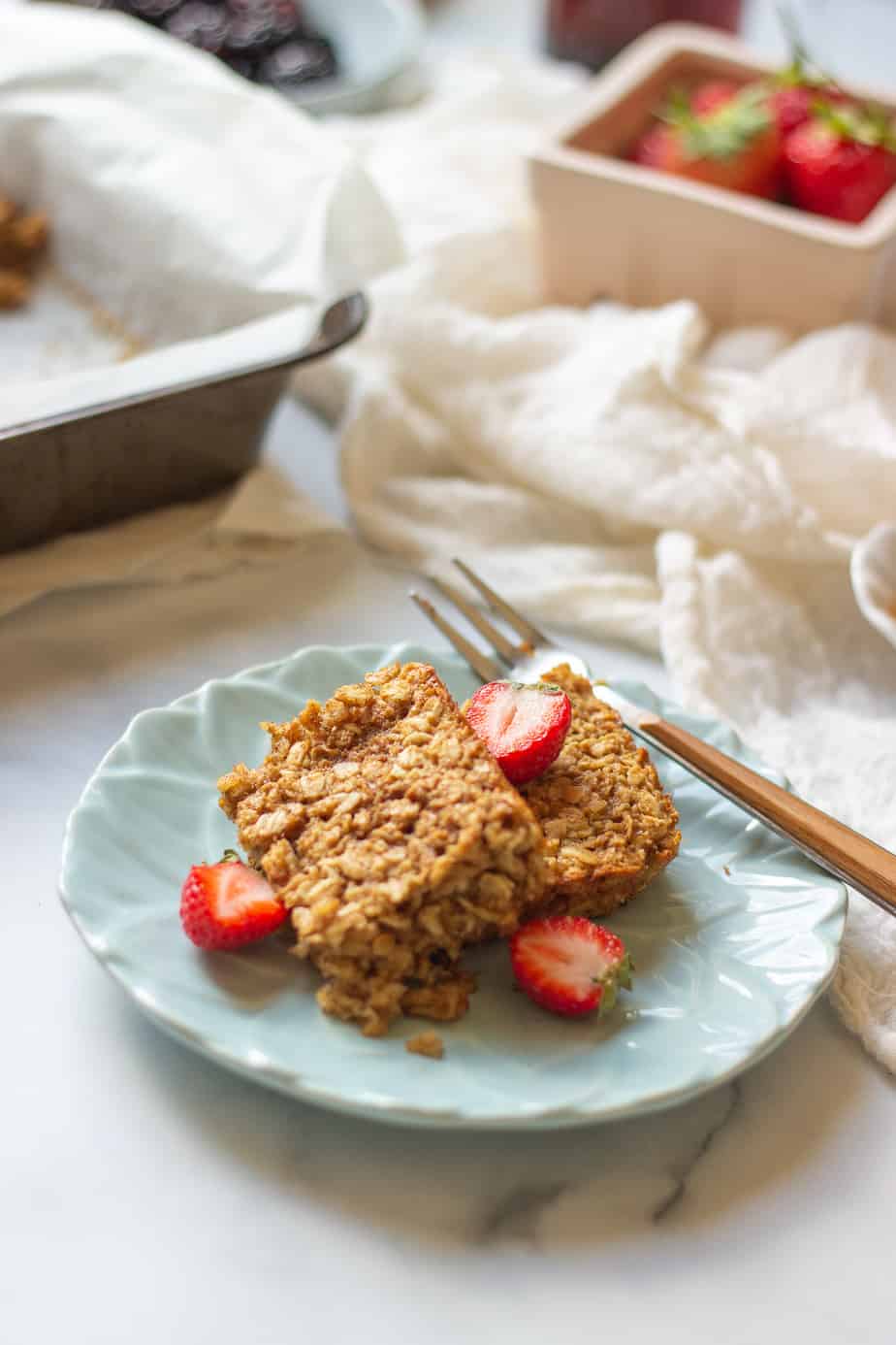 two squares of baked oats with cut up strawberries and on a blue plate