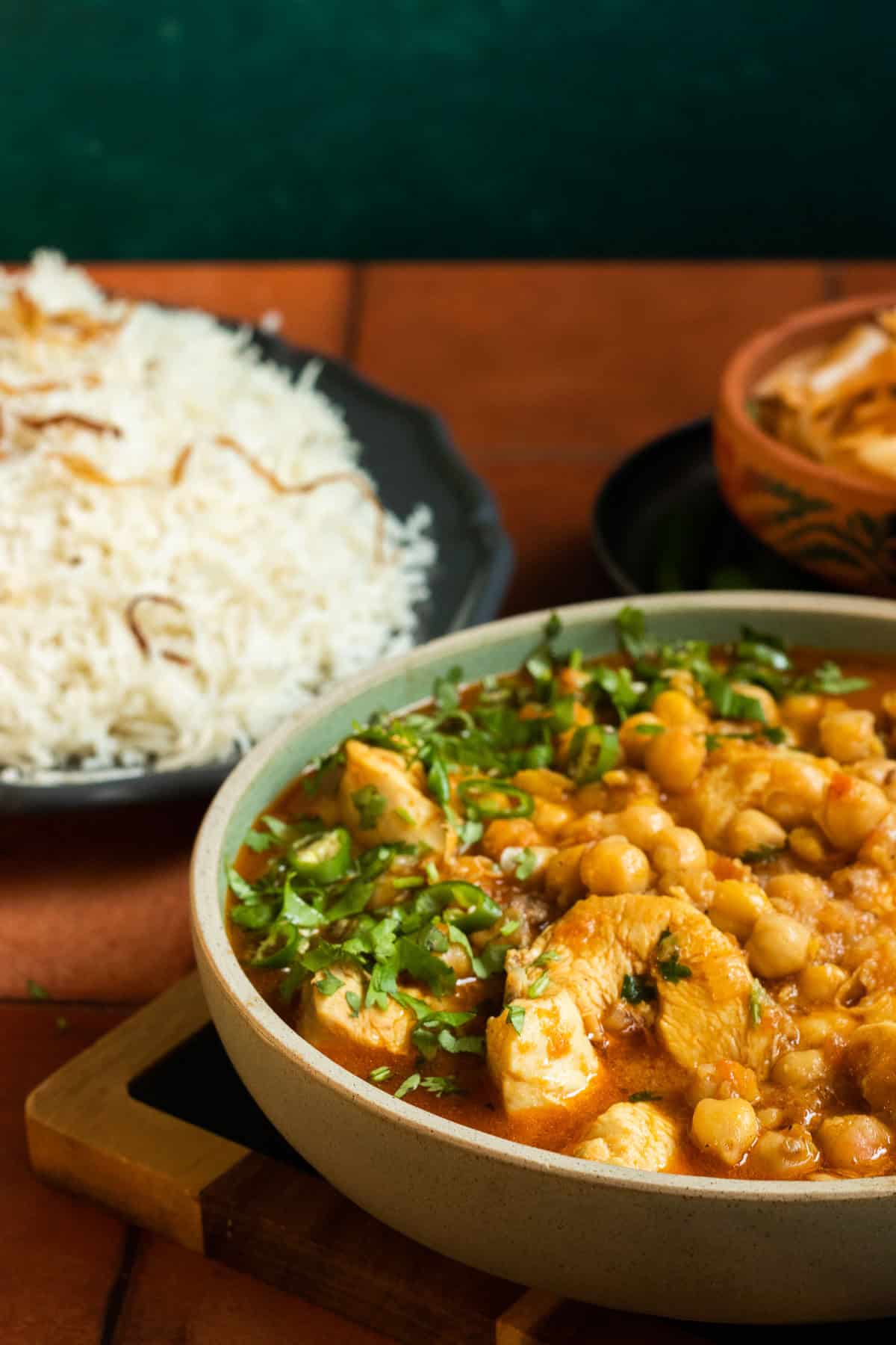 chana chickpea curry garnished in a bowl, rice in the background