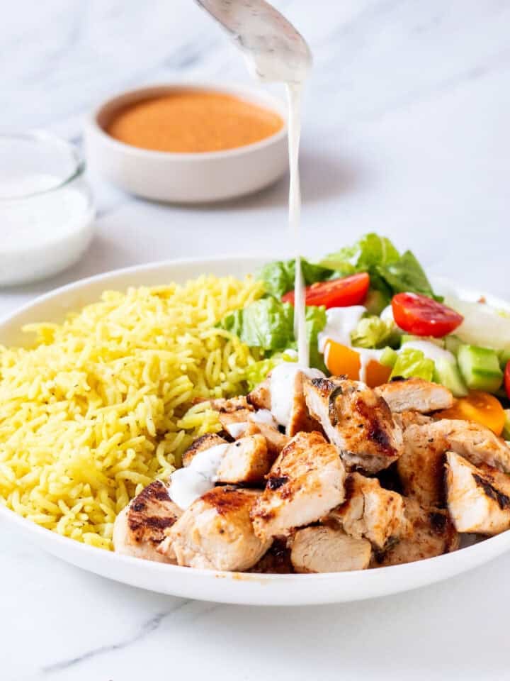 halal cart chicken and rice recipe with white sauce being poured on top