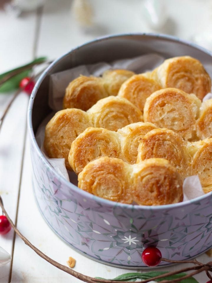 A 3/4 shot of a tin of french hearts with some christmas decor in the background