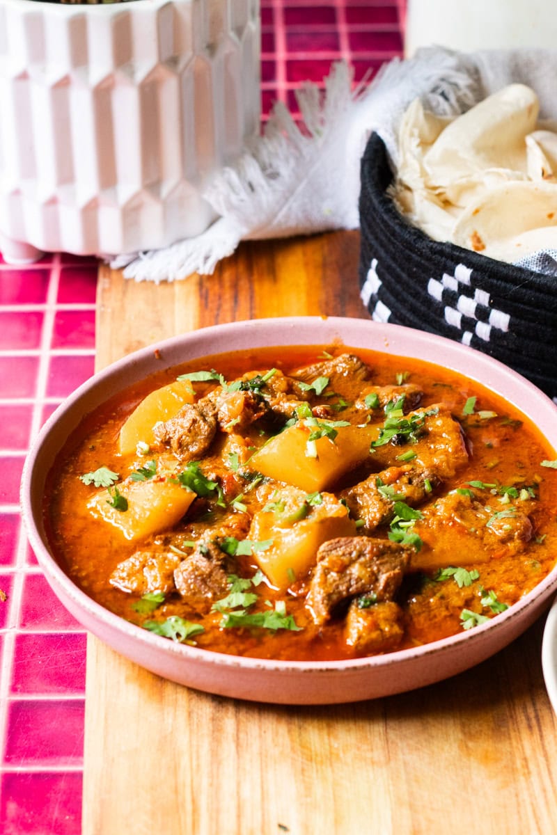 Aloo gosht in a bowl, romali roti in the back