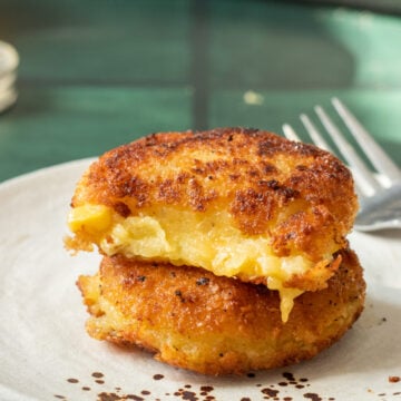 Aloo Cutlets stacked on top, one piece eaten out of the top one