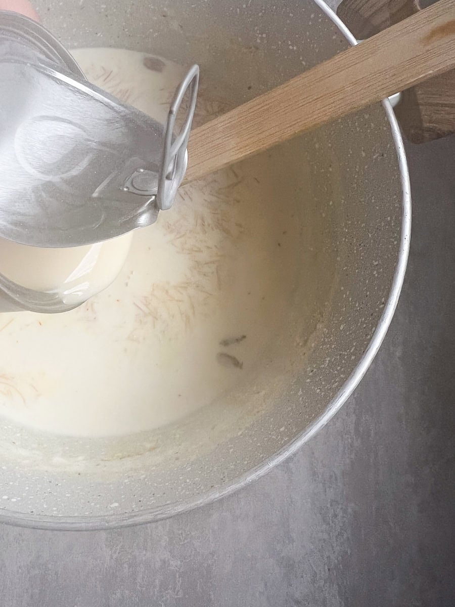 condensed milk being poured into a pot of sheer khurma