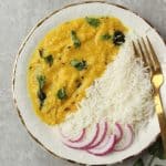 a plate of Khatti Daal with white rice and sliced red onions