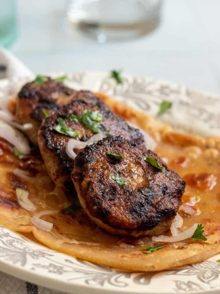 3/4 side view of three chicken kababs on top of a paratha