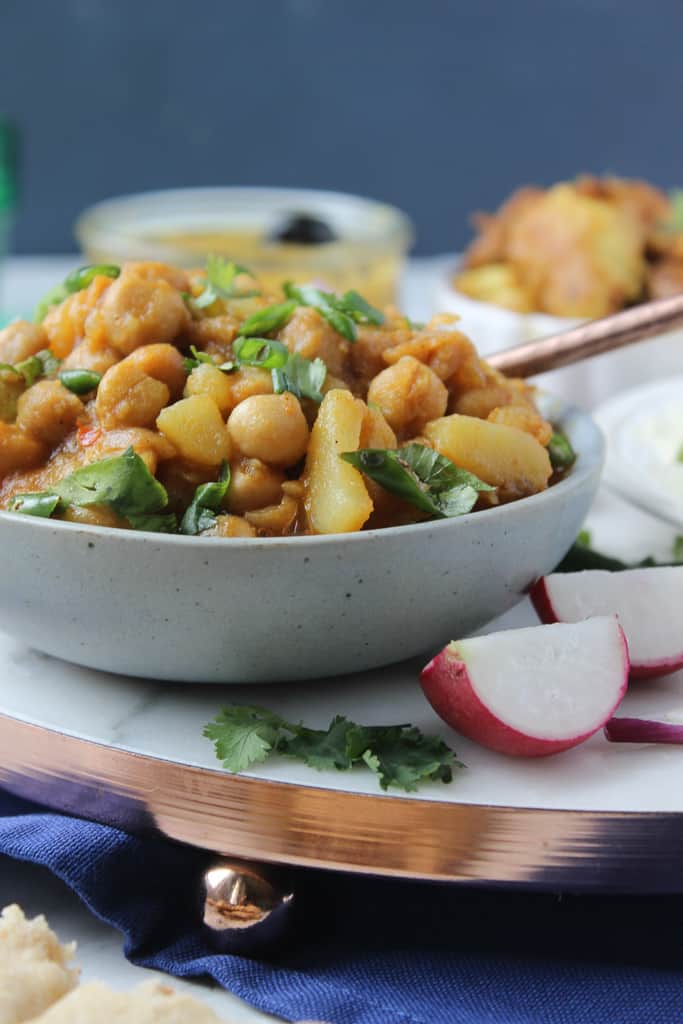 A bowl of aloo chana, two pieces of radish