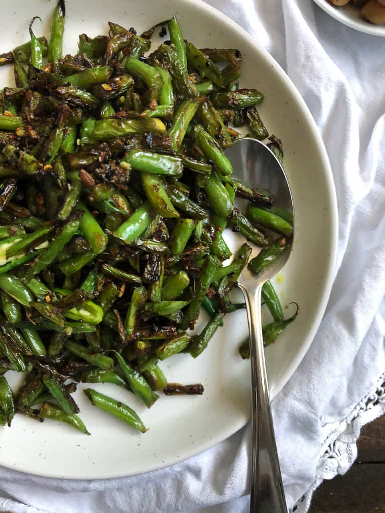 a white plate with lightly charred green beans