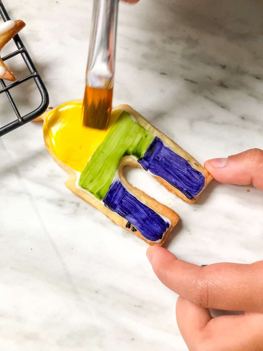 Eid cookeis being painted, brush and hand visible