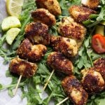 Three Sesame Ginger Chicken skewers on a bed of arugula