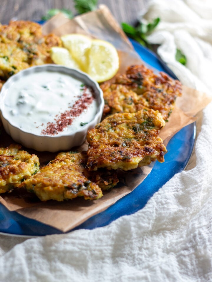 3/4 view of a plate of cauliflower fritters with the mint yogurt in the center