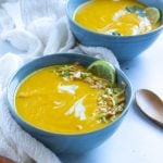 Three bowls of garnished instant pot carrot ginger soup, one showing fully and two partial