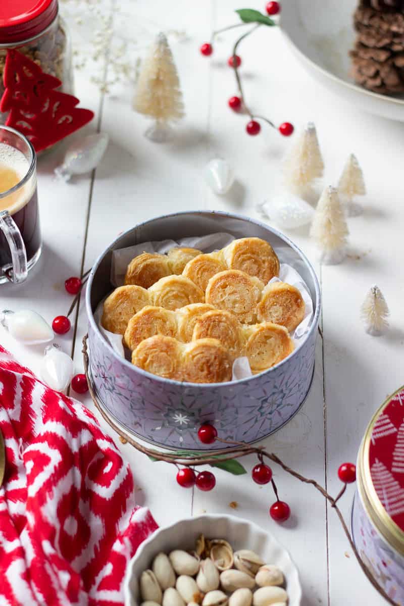 a tin of french hearts, mini white christmas trees, a cup of coffee and a partial view of a jar of granola