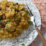 a ¾ view of a plate of dal gosht over rice