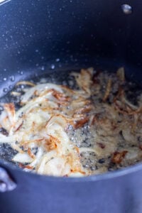 onions being sauteed in a black pot