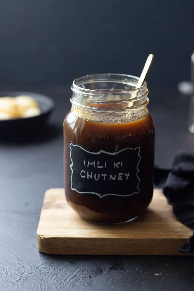 Imli ki Chutney in a jar, blurred pani puri in the background