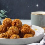 fried chicken balls mounded ina plate, a cup in the background