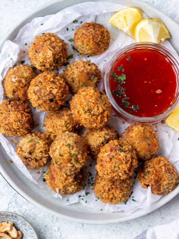 Crunchy Fried Chicken Balls on a plate with lemon wedges and hot sauce