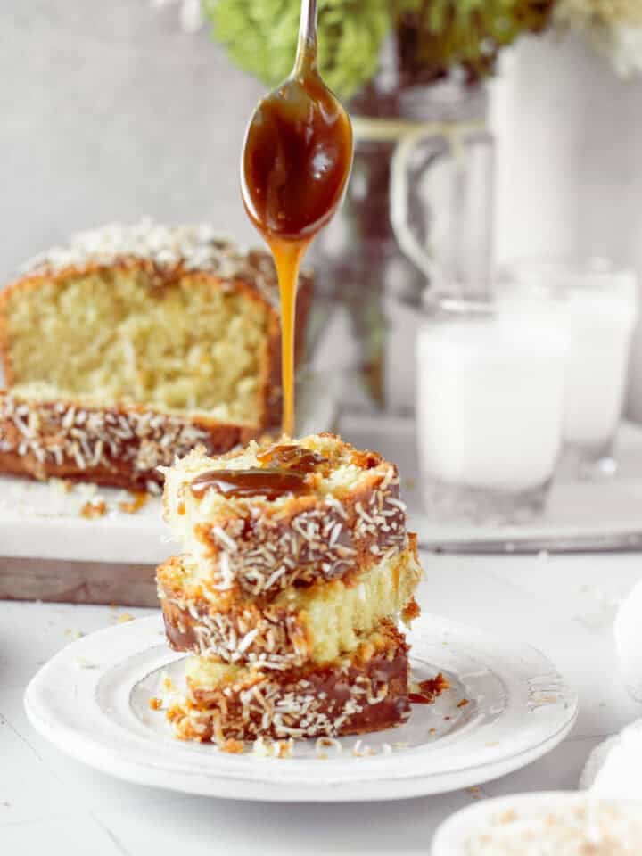 stack of 3 coconut cake slices with caramel sauce drizzling overtop