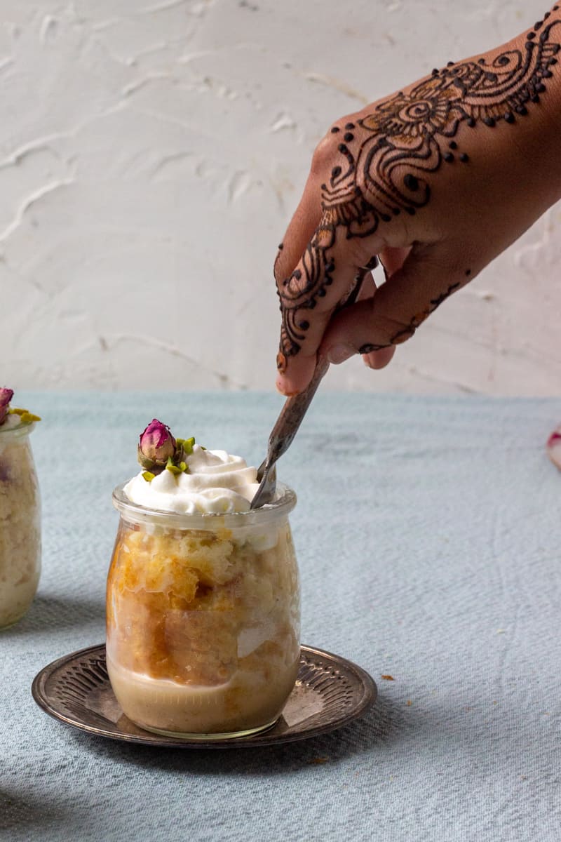 a hand with henna putting a spoon into Ras Malai Tres Leches Cake jar