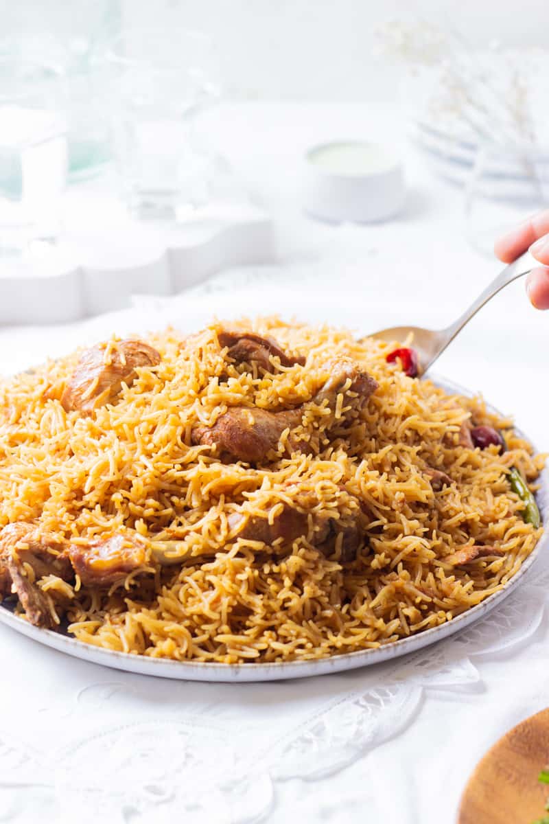 a cooked dish of pakistani chicken pulao with a spoon in it
