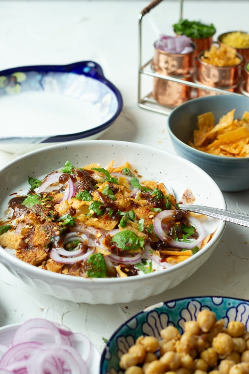 Mixed plate chaat assembled in a bowl, extra condiments in the background.