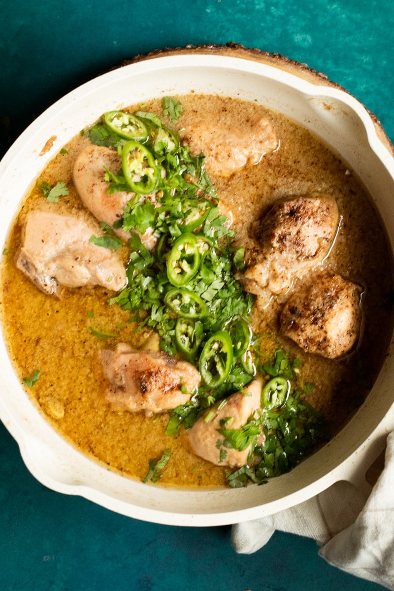A top down view of a white chicken curry with coriander and green chilies