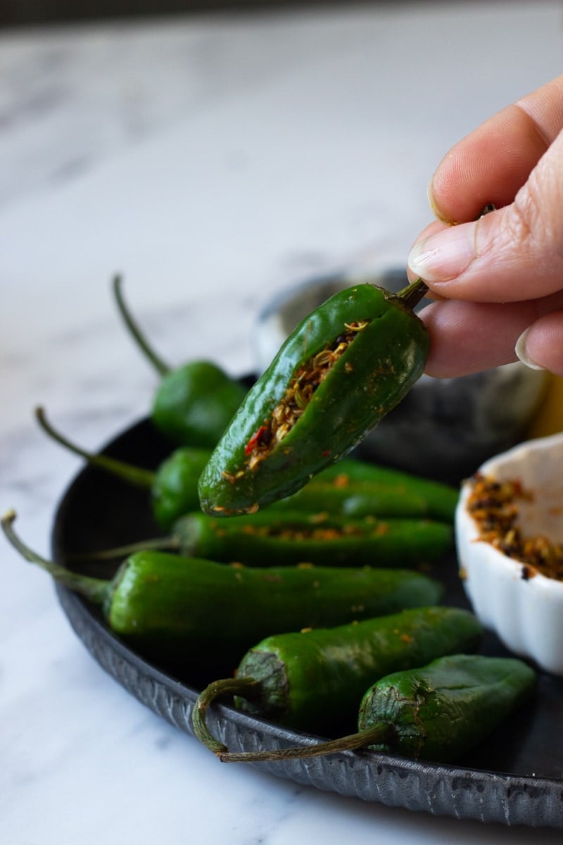 Achar Masala stuffed into chilies, held up by a hand