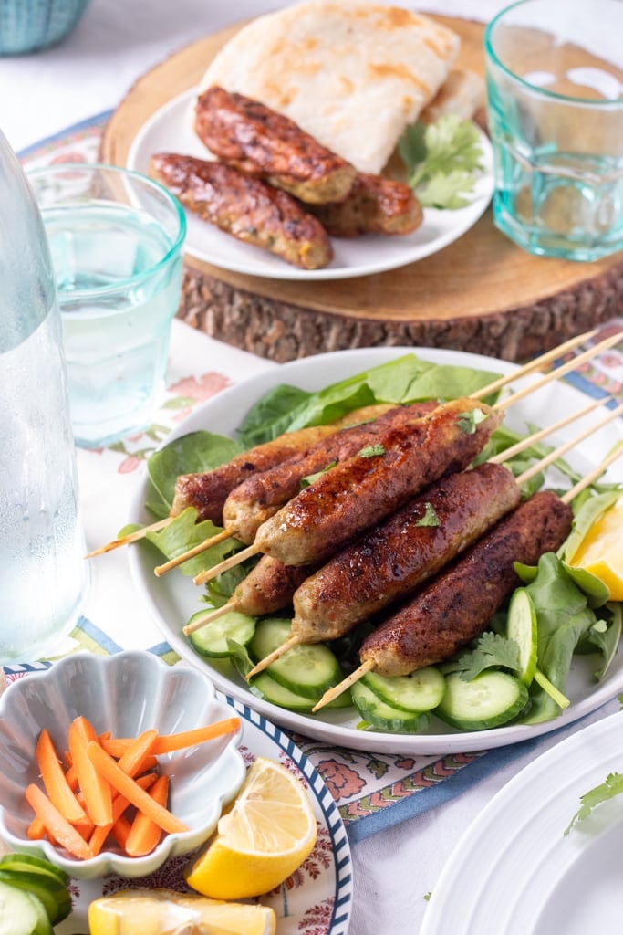 Chicken Seekh Kabab in two plates with water and veggies