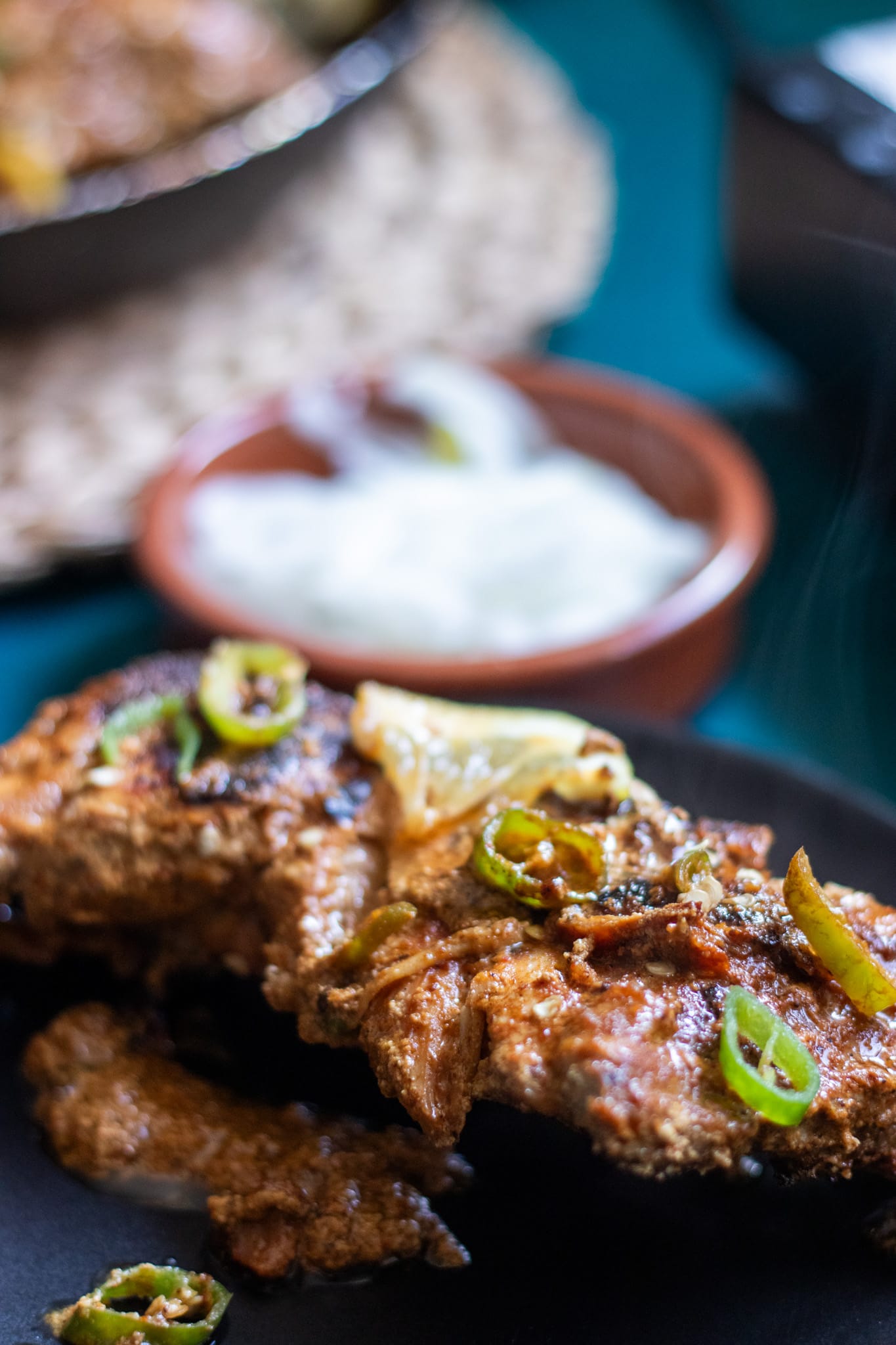one piece of tawa chicken, onions and skillet in the background