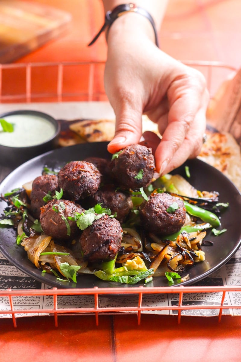 a hand reaching for a gola kabab