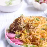 Pakistani Chicken Biryani on a plate along with pickled onions