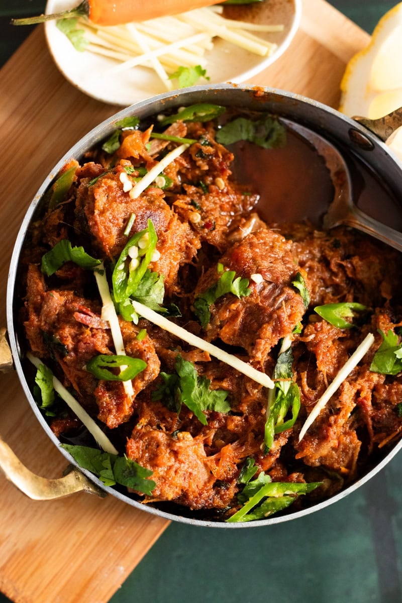 Karahi Gosht top down view with a bowl of ginger in the corner