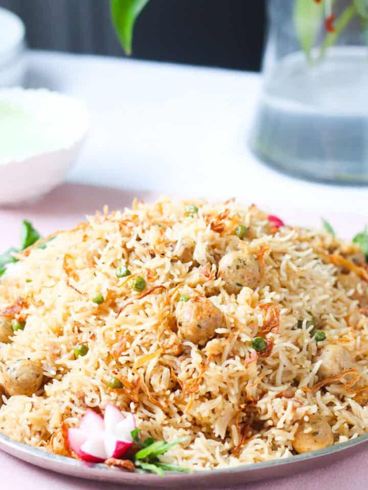 a dish of one pot moti pulao garnished with radishes and cucumbers