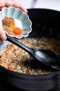 adding spices to handi masala